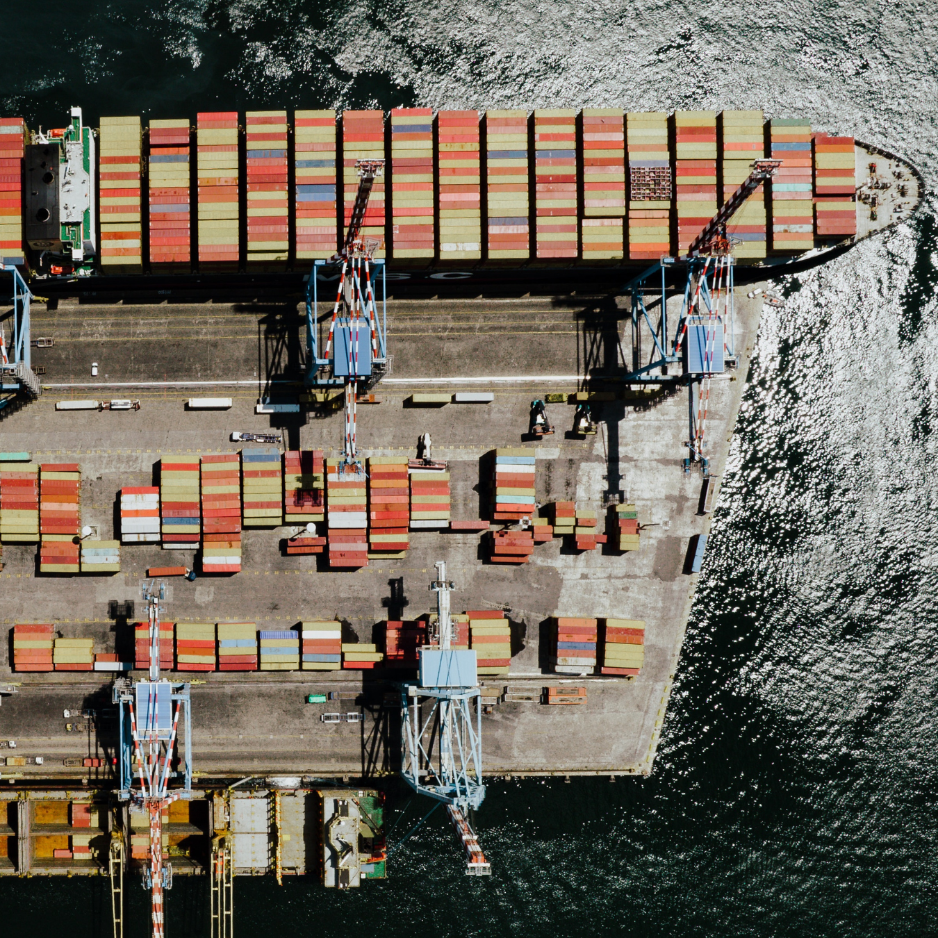 Aerial view looking down on a container ship being loaded at port.