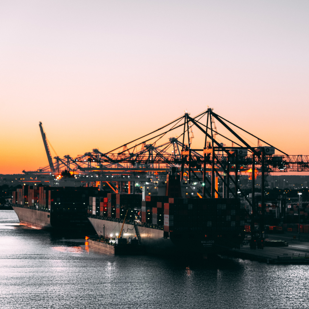 A container ship docked at port at sunset